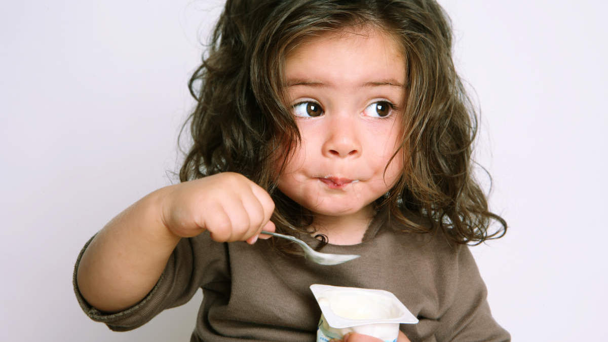 little girl with a spoon eating something